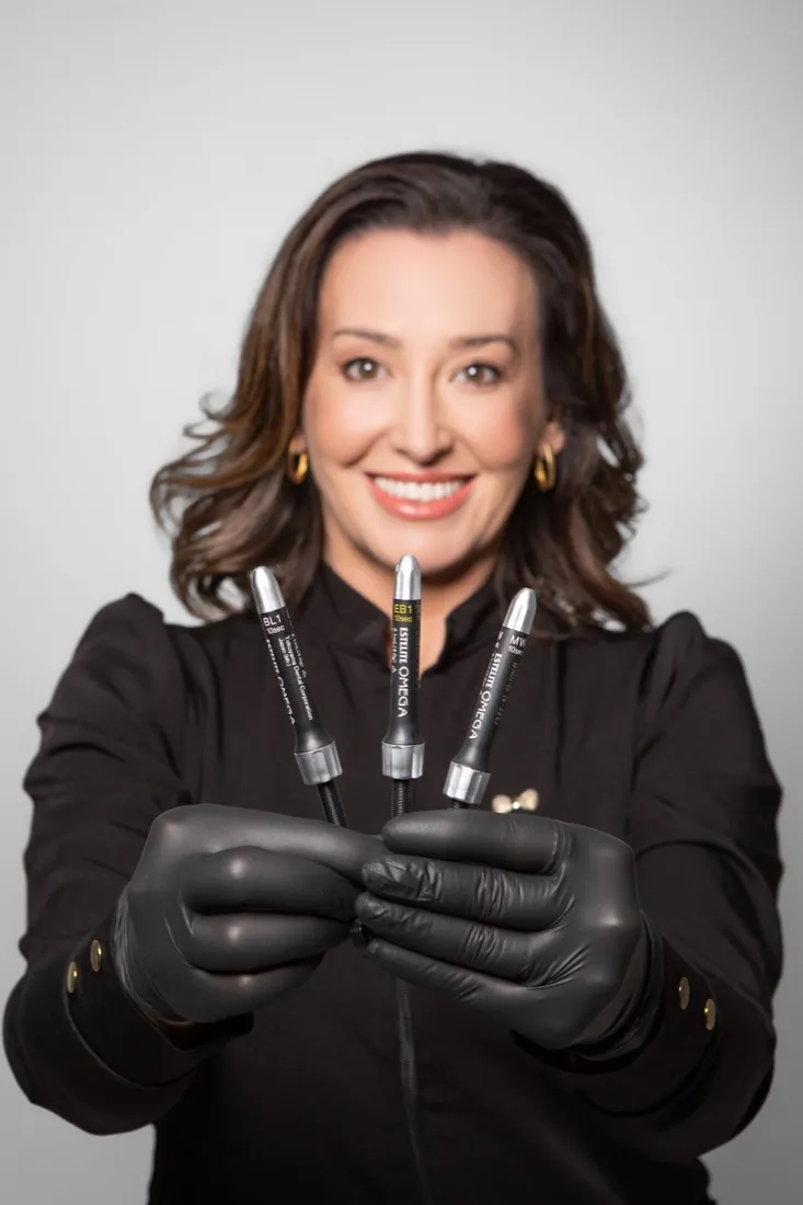 Dra. Cibele Rasera segurando materiais de resina usados nos tratamentos estéticos